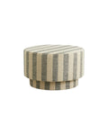 A round pouf with a linen cover featuring wide stripes in a sand-colored look, draped over the top.