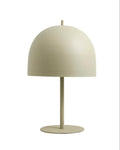 A matte beige table lamp with a white lampshade and a black iron base, standing on a fabric wire.