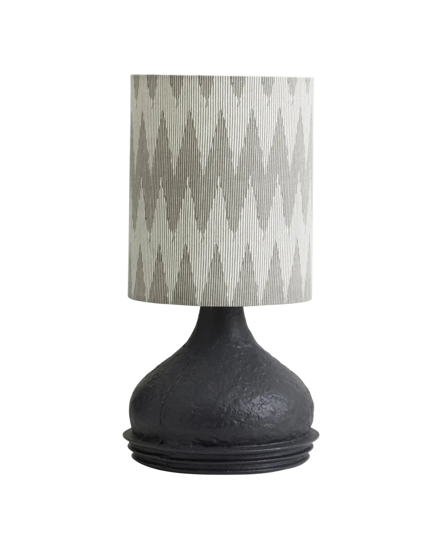 A black Arito table lamp with a fabric shade featuring a geometric pattern, placed on a flat surface.